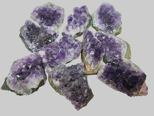 Amethyst crystal clusters on a white surface - Earthstore UK