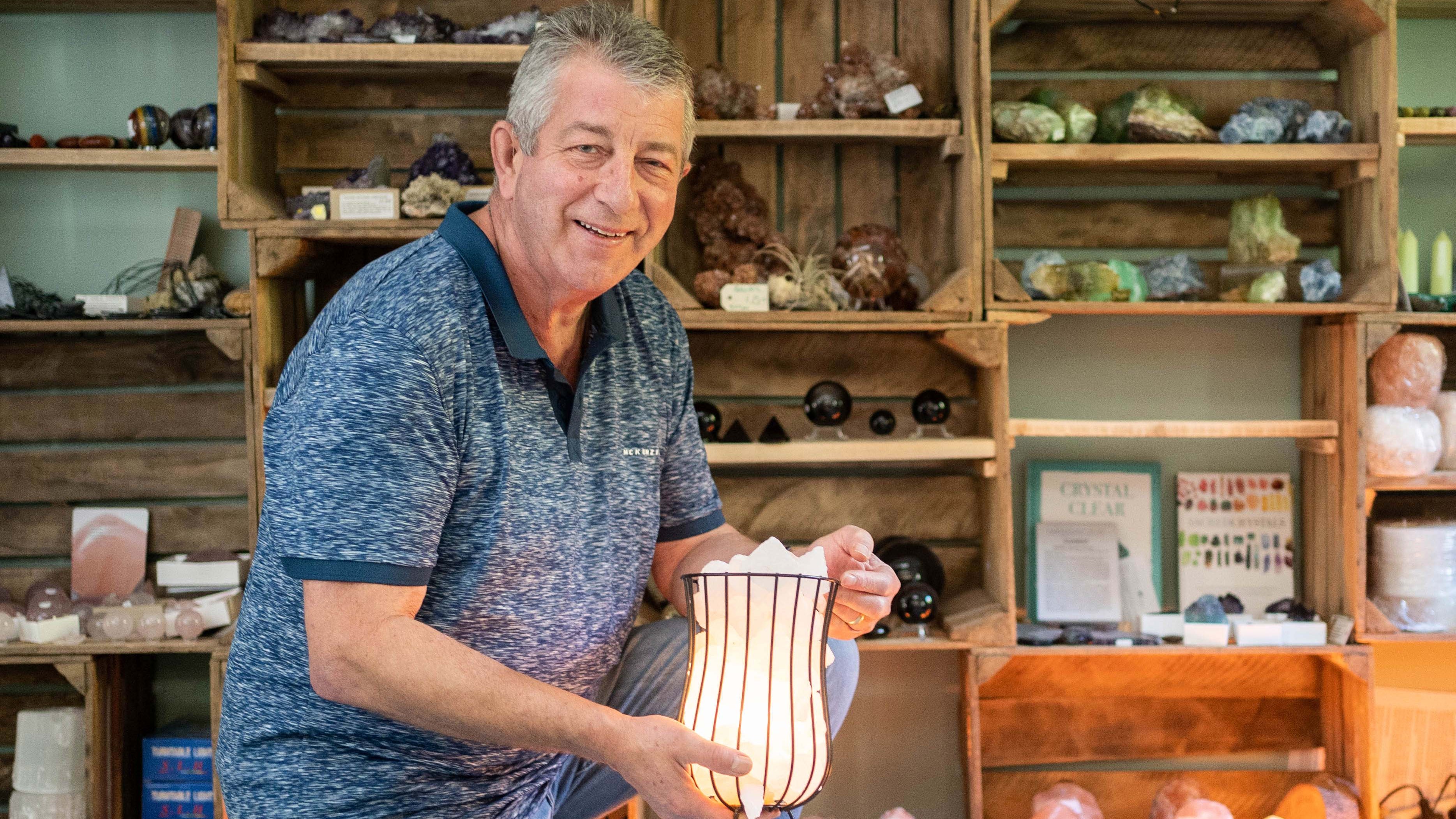 Nigel holding a salt lamp in a Earthstore with shelves displaying various items