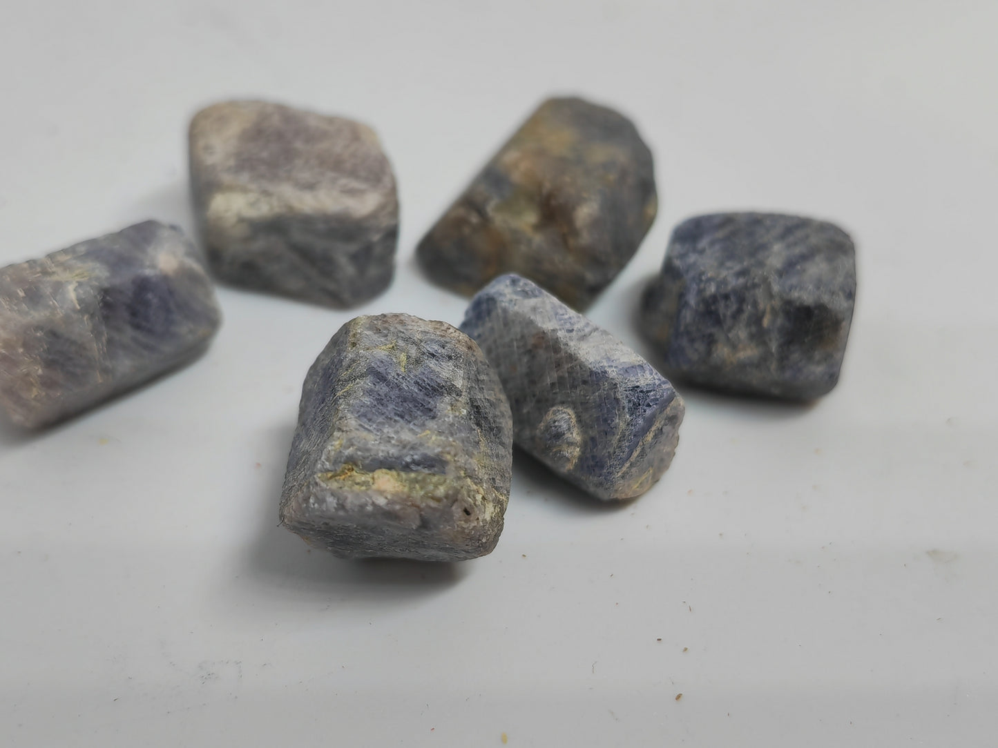 Raw sapphire stones on a light gray background